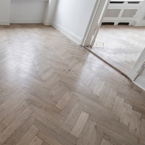 A dull, grimy parquet floor before an A+ clean